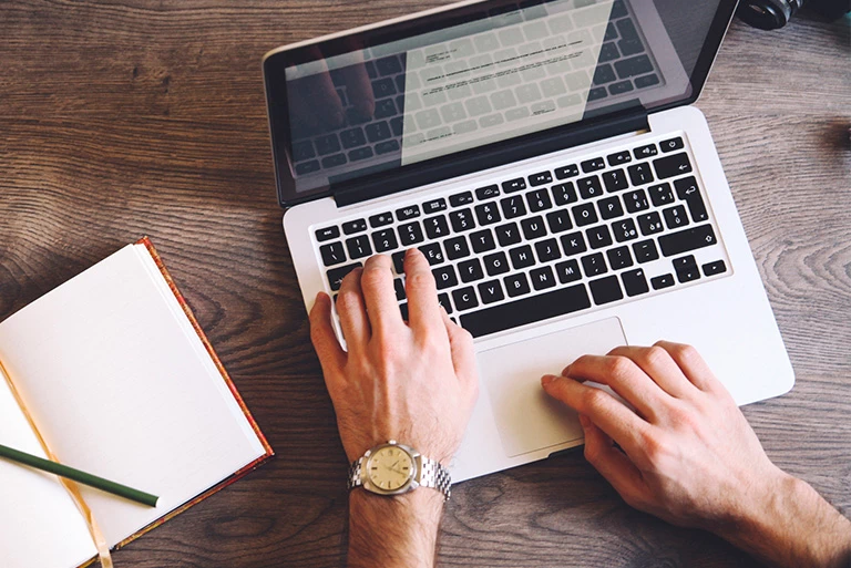 Kobieta pisząca tekst na&nbsp;laptopie